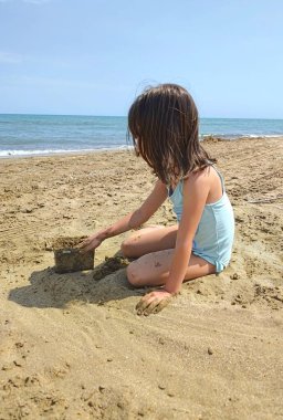Küçük kız kumsalda kumla oynuyor. Yüksek kalite fotoğraf