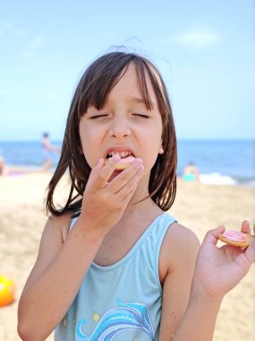 Küçük kız sahilde kurabiye yiyor. Yüksek kalite fotoğraf