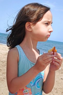 Küçük kız sahilde kurabiye yiyor. Yüksek kalite fotoğraf