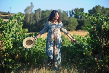 Üzüm bağında hasır şapka ve elbise içinde güzel genç bir kadın.