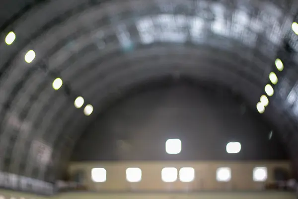 Yumuşak odak noktasının ışık ve yapıyı neredeyse rüya gibi soyut bir kompozisyona dönüştürdüğü, kemerli bir iç tavanın bulanık bir görüntüsü. Işıkların parıltısı sıcaklık ve gizem katıyor..