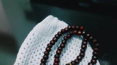 Müslüman dua şapkası ve ahşap tasbih boncukları, bağlılığı ve maneviyatı sembolize eder.