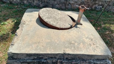 Teftiş kapağı kısmen kaldırılmış bir rögar deliği, kanalizasyonları, kanalizasyonları veya kamu hizmetleri tünellerini kontrol etmek için kullanılan açığı gösterir, genellikle bakım sırasında ya da tıkanma tıkanmalarını denetlemek için erişilir