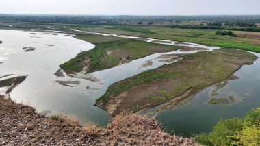 Punjab 'daki Sawan Nehri' nin güzel bir manzarası, etrafını çevreleyen tepeleri çevreleyen yemyeşil bitkiler ve çalılarla birden fazla kanaldan akan, huzurlu doğal bir manzara yaratıyor.