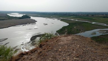 Punjab 'daki Sawan Nehri' nin güzel bir manzarası, etrafını çevreleyen tepeleri çevreleyen yemyeşil bitkiler ve çalılarla birden fazla kanaldan akan, huzurlu doğal bir manzara yaratıyor.