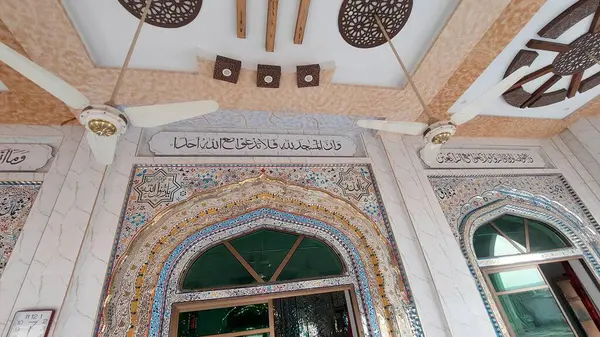 Güzel tasarlanmış bir tavan ve çatıdan sarkan pervanelerle tamamlanmış, ağırlıklı olarak cam kaplama duvarlar ve Arapça kaligrafi içerir.