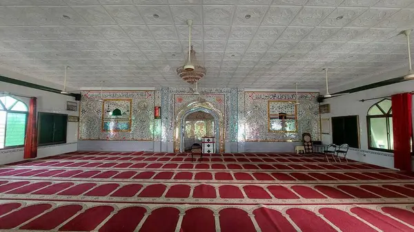 Huzurlu ve süslü bir iç mescit ağırlıklı olarak cam kaplama duvarlar, karmaşık desenler ve Arapça kaligrafi ile süslenmiş, zemin ise kırmızı dua paspaslarıyla düzgünce sıralanmış, ruhani ortamı geliştiren