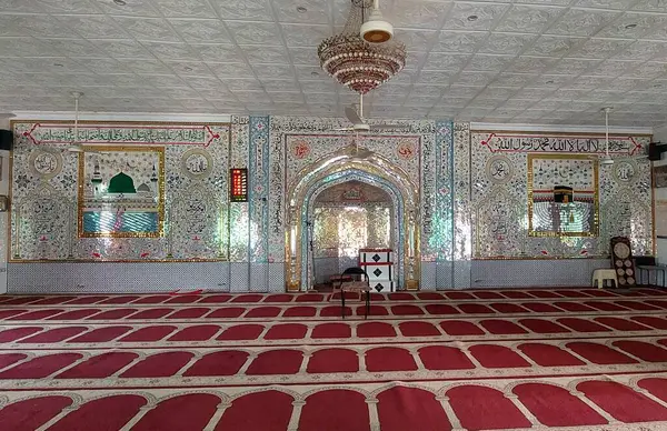 Huzurlu ve süslü bir iç mescit ağırlıklı olarak cam kaplama duvarlar, karmaşık desenler ve Arapça kaligrafi ile süslenmiş, zemin ise kırmızı dua paspaslarıyla düzgünce sıralanmış, ruhani ortamı geliştiren