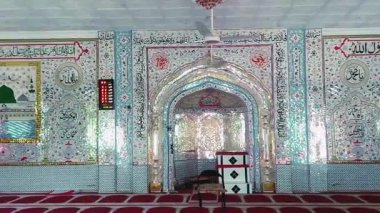 Huzurlu ve süslü bir iç mescit ağırlıklı olarak cam kaplama duvarlar, karmaşık desenler ve Arapça kaligrafi ile süslenmiş, zemin ise kırmızı dua paspaslarıyla düzgünce sıralanmış, ruhani ortamı geliştiren