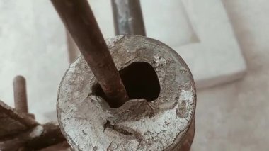 Köy evinin beton yapısının köşesinde, yanında su toplamak için iki kil çömlek bulunan paslanmış ve aşınmış eski bir el suyu pompası duruyor. Pompa yıpranmış ve muhtemelen tam işlevsel değil.