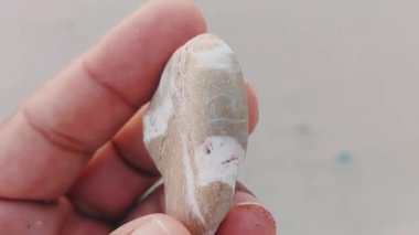 Karmaşık doğal desenlere, çizgilere, noktalara ve belirgin jeolojik oluşumunu vurgulayan çarpıcı renklere sahip eşsiz şekilli bir taş.