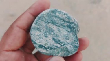 Karmaşık doğal desenlere, çizgilere, noktalara ve belirgin jeolojik oluşumunu vurgulayan çarpıcı renklere sahip eşsiz şekilli bir taş.