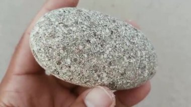 Karmaşık doğal desenlere, çizgilere, noktalara ve belirgin jeolojik oluşumunu vurgulayan çarpıcı renklere sahip eşsiz şekilli bir taş.