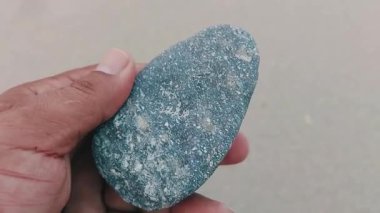 Karmaşık doğal desenlere, çizgilere, noktalara ve belirgin jeolojik oluşumunu vurgulayan çarpıcı renklere sahip eşsiz şekilli bir taş.