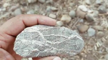 Karmaşık doğal desenlere, çizgilere, noktalara ve belirgin jeolojik oluşumunu vurgulayan çarpıcı renklere sahip eşsiz şekilli bir taş.
