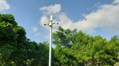 Parlak Mavi Gökyüzü ve Yeşil Yapraklara Karşı Yüksek Bağlı Çoklu Mercek Güvenlik Kamerası