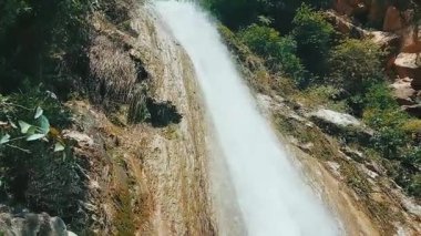 Vertical shot of beautiful waterfall cascading over mossy rock face with natural peaceful sound