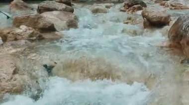 Dynamic close up view of fast moving turquoise stream with rapids and waterfalls