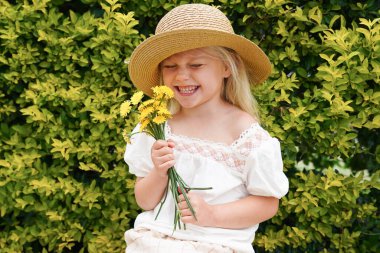 Elinde çalı arkaplan demeti olan şapkalı, tatlı, gülen kız. Yüksek kalite fotoğraf