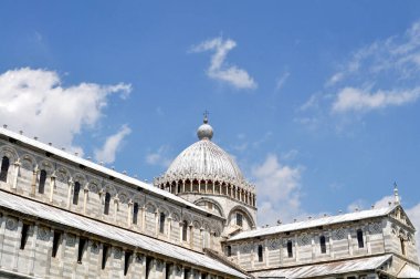 Pisa kulesinde üzerinde haç olan bir Katedral Kubbesi mavi bir gökyüzünün altında.