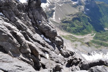 Dağ zirvesinden İsviçre dağlık yaylalarının kayalık ve karlı manzarası nefes kesici.