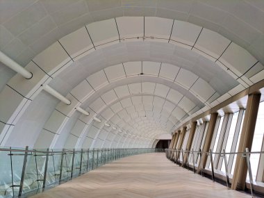 Arched or curved ceiling with light steel frame and aluminium composite panel materials, with ceiling finished in perforated metal. Showing some skylight with curved structure. clipart