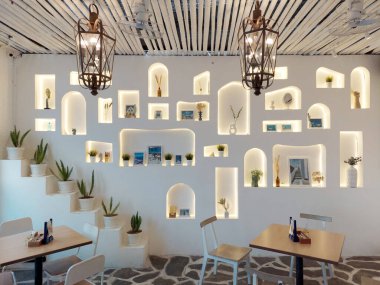 Çamurdan yapılmış seramik sergiler, beyaz duvar kaplamaları, dokulu beyaz boya çıkıntıları, seramik tencerelerin açık oyukları, ekran..