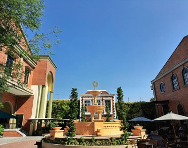 Modern Avrupa klasik malikanesinin İtalyan ve Akdeniz temalı müsrif malikanesi, teras yemek alanında yeşillikler ve çamlar, ve ortasında klasik su çeşmesi..