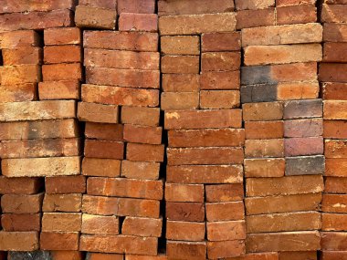 Üst üste yığılmış kırmızı tuğla yığınları. Kırmızı tuğlalar inşaat alanında kullanılan duvar malzemeleridir..