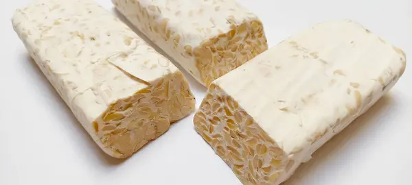 stock image Sliced tempe or tempeh, a typical traditional Indonesian fermented soybeans, using fungi called Rhizopus. Isolated on a white background.