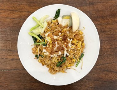 Yerel Java geleneksel pilavı, lahanalı ve çırpılmış yumurtalı, beyaz tabağın üstünde, ahşap bir masada servis edilir..