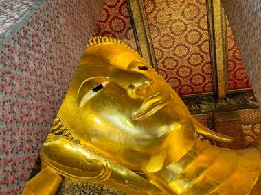 The famous Reclining Buddha statue in Wat Pho Temple, Bangkok, Thailand. Reclining Buddha inside Wat Pho made of gold materials. clipart