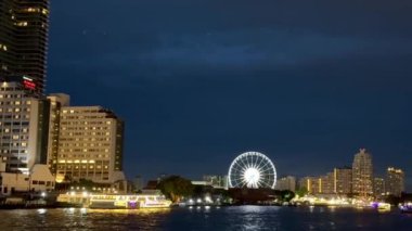 Bangkok 'un ünlü nehri Chao Phraya Nehri' nden Bangkok 'u kesen gökdelenlerin panoramik görüntüsü. Video, gün batımında Bangkok 'ta nehir kıyısında bir feribottan çekilmiş.