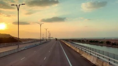 Ünlü Hong Kong-Zhuhai-Macau Köprüsü ya da HZMB 'den geçen kara yolculuğunun videosu, açık deniz, kara ve deniz manzarasını aşan uzun köprü, romantik günbatımı gökyüzünü görür..