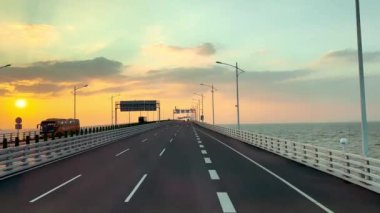 Ünlü Hong Kong-Zhuhai-Macau Köprüsü ya da HZMB 'den geçen kara yolculuğunun videosu, açık deniz, kara ve deniz manzarasını aşan uzun köprü, romantik günbatımı gökyüzünü görür..