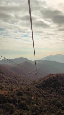 Hong Kong, Lantau Adası 'ndaki Ngong Ping 360 teleferiğinin nefes kesici görüntüsü. Günbatımı gökyüzünde çekilmiş bir video. Teleferikle ünlü tepeleri ve kırsal bölgeleri yukarıdan gören.