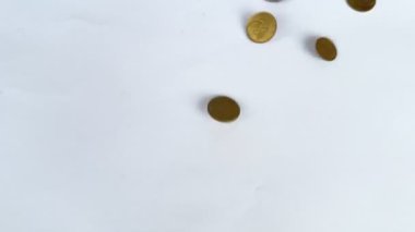 Dünyanın çeşitli para birimlerinden gelen para birimlerinin 4k 'lık görüntüsü, yere düşüyor, dağılıyor ve beyaz arka plan yüzeyine yayılıyor. Bozukluklar düşüyor, para tasarrufu konsepti. Küresel kriz ve enflasyon.