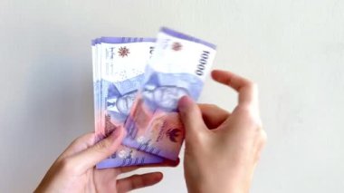 Endonezya Rupiah 'ının Rp10.000. seviyesinde el ve parmak sayımının 4K görüntüleri. Beyaz arka planda izole edilmiş IDR 10K banknotlarını sayan eller.