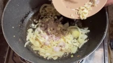 Kızarmış soğan, dilimlenmiş ve doğranmış sarımsak ve soğan ile birleştirilmiş, kızartma tavasında karıştırılmış ve karıştırılmış, ev yapımı başlangıç için kızartılmış soğan sosu karıştırılmış..