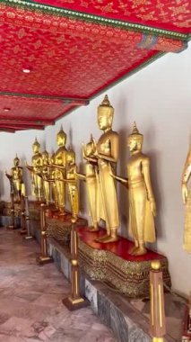 Wat Pho Tapınağı, Bangkok, Tayland 'da Buda heykelleri serisi. Altın metalik renklerle boyanmış, kaidede duran Buda 'nın serisi.