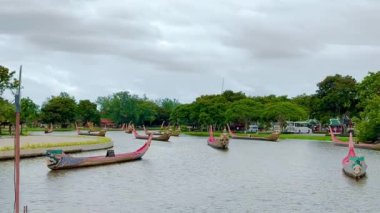 Bulutlu bir gökyüzünün altında, nehirde yüzen ve gezinen geleneksel Thai yatı görüntüsü. Tayland geleneksel uzun kürek teknesi, günümüzde Chao Phraya nehrinde hala insanların kullandığı bir miras..