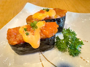 Somon balıklı suşiyi deniz yosunu ya da nori ile sarmalayıp porselen bir Japon tabağında servis et. Japon yemek teması.