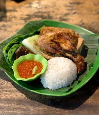 Fried chicken with fermented soy, rice, and cucumber dressing, with typical Indonesian traditional chili onion. Traditional Indonesian food. clipart