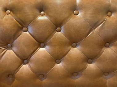 Kahverengi deri kanepeyi boncuklarla kapatın. Klasik kanepe yastığı, klasik kahverengi hakiki deri, parlak yarı parlak döşeme paneli için uygun, yumuşak koltuklar. Kusursuz arkaplan dokusu.