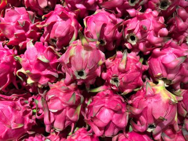 Yerel bir meyve pazarında, siyah sepetin üzerinde, bir dizi ejderha meyvesi yakın. Ejder meyvesi kan şekerini düşürmek, kalp sağlığını korumak ve kanser potansiyelini azaltmak konusunda ünlüdür..