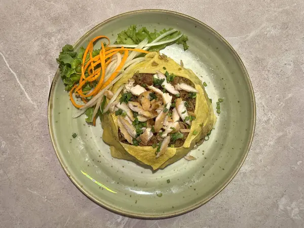 Geleneksel Java Tavuğu Kızarmış Pirinci, Endonezya ve çevresi için özgün bir kızarmış pirinç, omlet ve marulla kaplanmış, yeşil bir tabakta servis ediliyor..