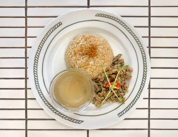 Salamura edilmiş tavuğu biberiye, şifalı ot, pirinç ve zencefilli tavuk soslu çorbayla kapat. Tavuklu pilav fotoğrafçılığı. Beyaz döşeme masası.