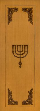 Ortalarında Menorah sembolü olan ahşap süsleme çerçevesini kapat. Menorah, Musevilikte ve Hristiyanlıkta Allah 'ın tapınağında kullanılan yedi dallı bir mumdur. Dini oyma sembolleri.