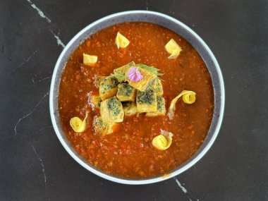 Koyu kırmızı soslu mapo tofu 'ya yakın çekim. Mapo tofu Güney Çin kökenli tipik bir Çin Hakka mutfağıdır. Gri bir tabakta, siyah bir mermer masada servis edildi..