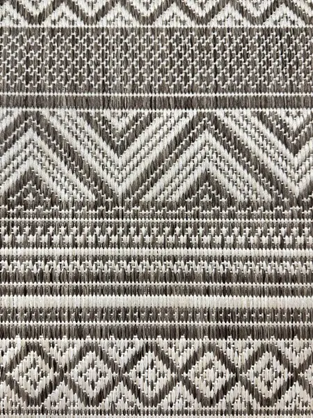 El yapımı geleneksel örülmüş halı dokusunu beyaz ve gri siyah renklerle kapatın. Şevron, elmas ve şerit desenli el örgüleriyle dikilmiş klasik halı kavramı. pürüzsüz arkaplan.